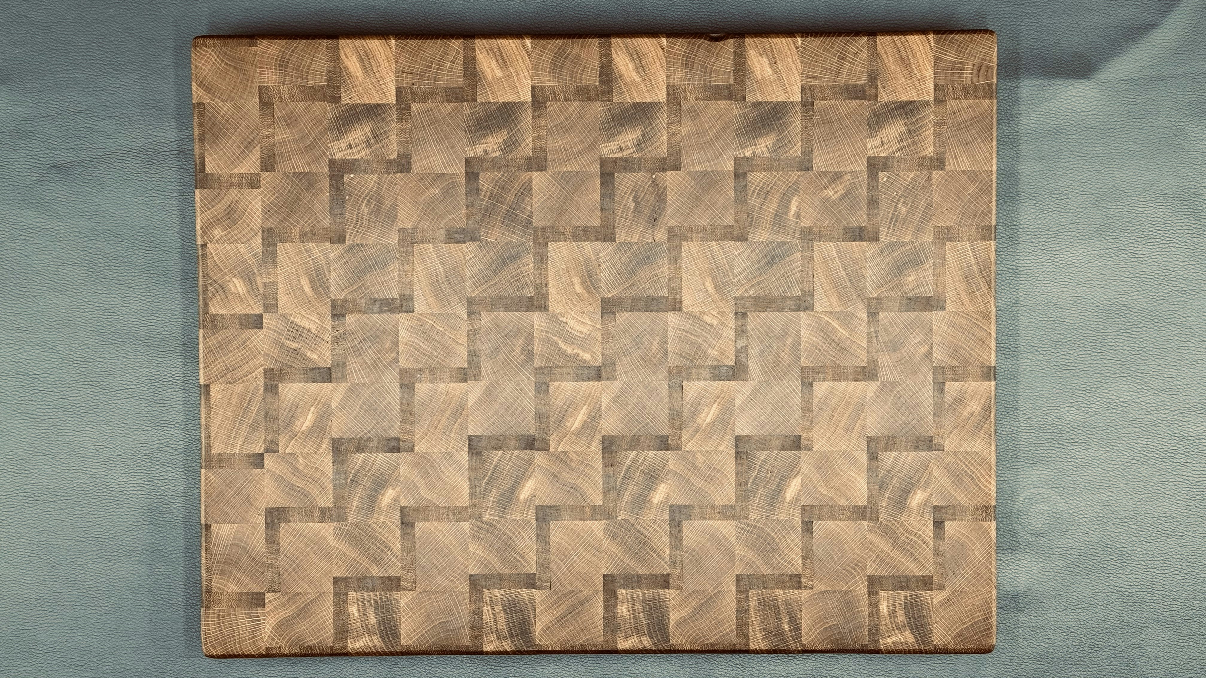 Close-up of a woven end-grain cutting board showing alternating light and dark wood squares in a checkerboard pattern