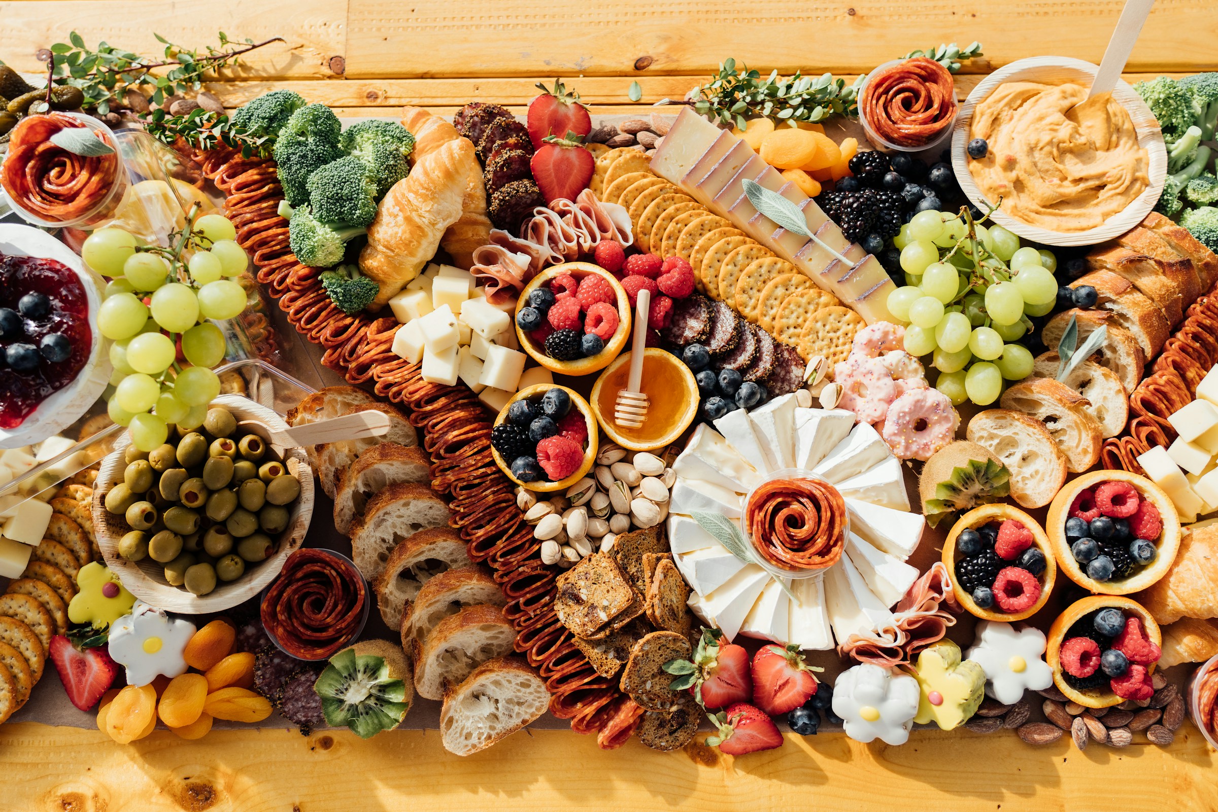 An overhead view of a charcuterie board spread with cured meats, cheeses, grapes, and crackers arranged on a wooden board