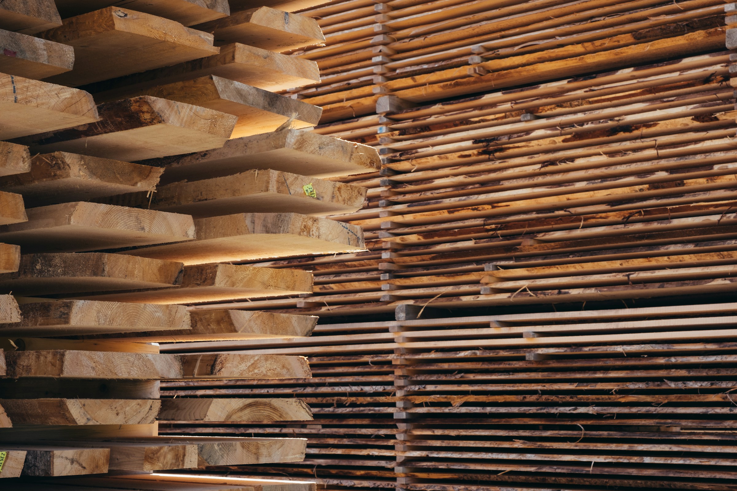 Stacked hardwood lumber planks at a lumber yard, showing rich brown tones and natural wood grain
