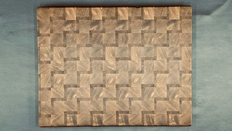 Close-up of a woven end-grain cutting board showing alternating light and dark wood squares in a checkerboard pattern