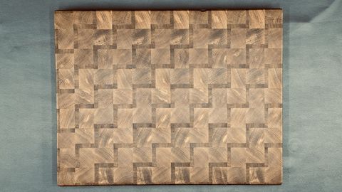 End-grain cutting board with a geometric woven wood pattern on a clean light surface