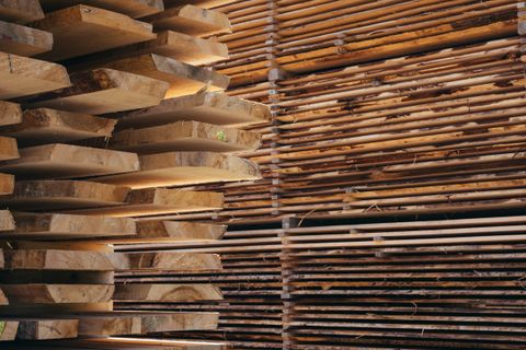 Stacked hardwood lumber planks at a lumber yard, showing rich brown tones and natural wood grain