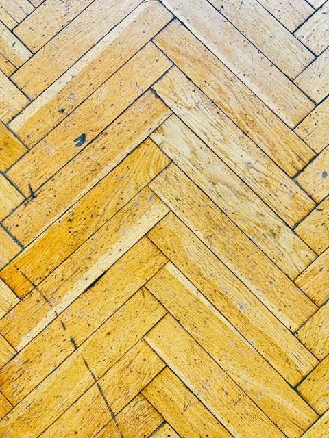 Close-up of a herringbone wood pattern with alternating light and dark strips forming a V-shaped zigzag